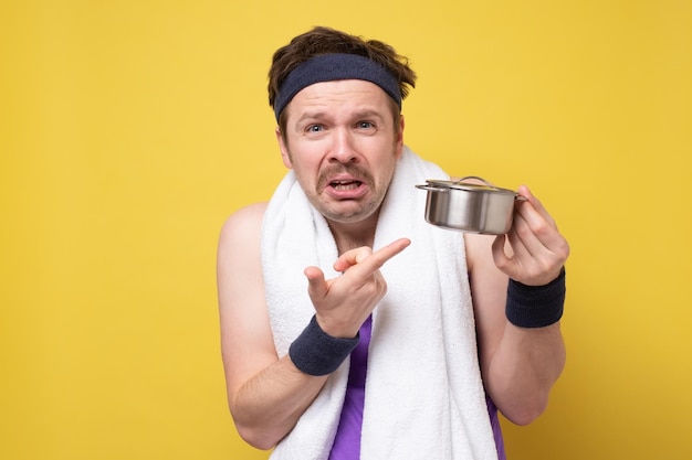 Homme perplexe à la recherche de nourriture dans une petite casserole contrarié par son dîner