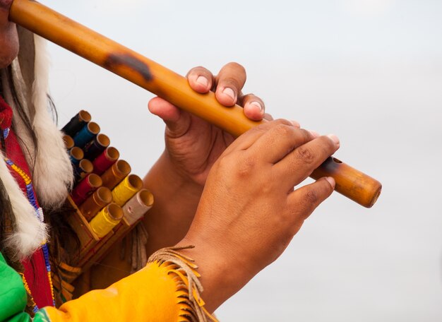 Homme péruvien en costume autochtone jouant de la flûte