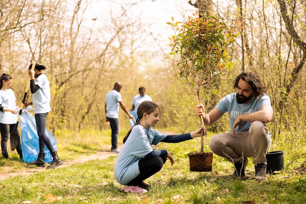 Un homme et une petite fille s'associent et plantent un arbre ensemble dans les bois.