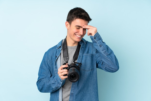 Homme photographe adolescent isolé sur bleu rire