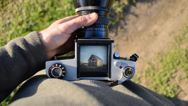 L'homme photographe fait de la photographie d'arhitecture avec un vieil appareil photo argentique dans la maison de printemps et le concept de bâtiment vue de dessus copyspace
