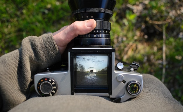 L'homme photographe fait de la photographie de paysage avec un vieil appareil photo argentique au printemps ou en été tourisme et randonnée concept vue de dessus copie espace