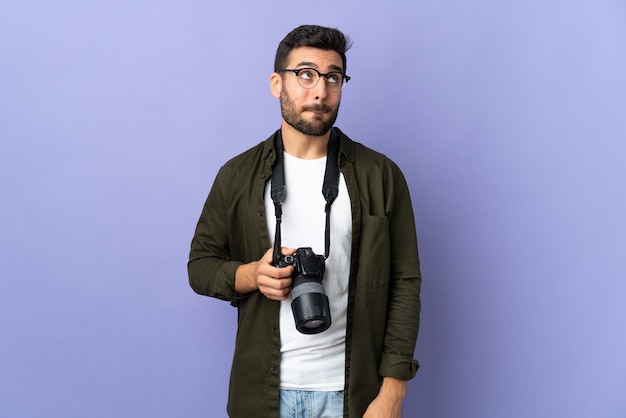 Homme photographe sur mur violet isolé ayant des doutes tout en regardant