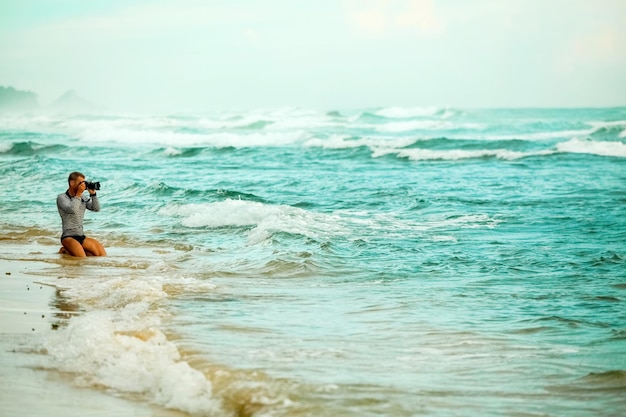 Homme photographiant les vagues sur la plage de l'Océan Indien