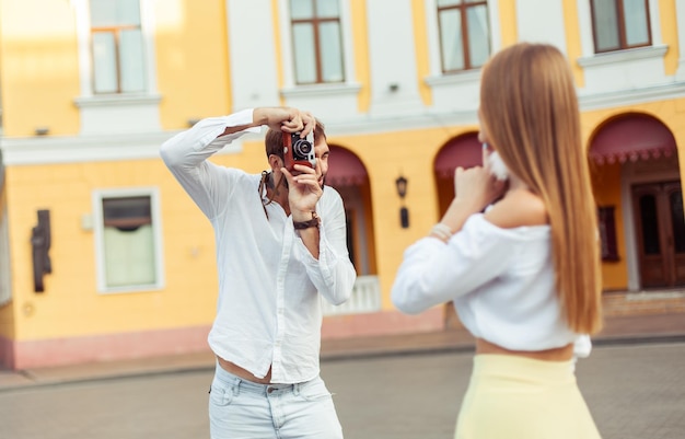 Un homme photographie une belle jeune femme en ville.