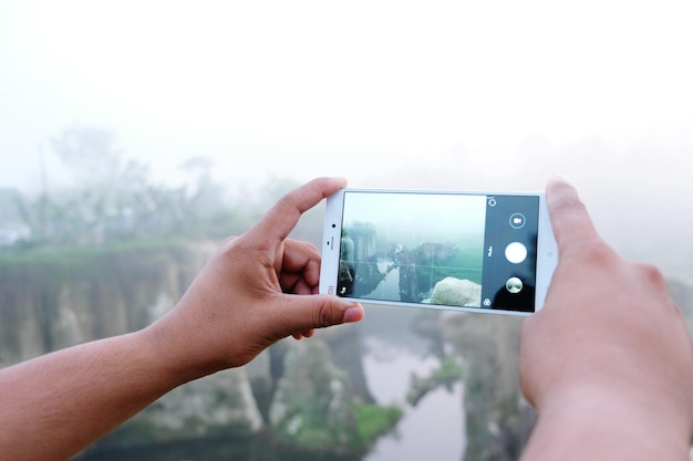Un homme photographie avec son téléphone portable contre le ciel