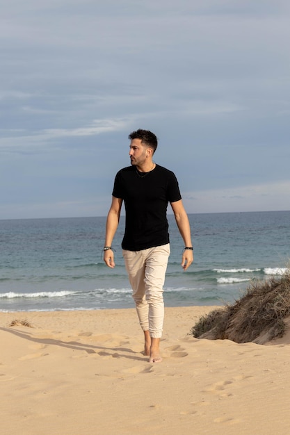 Photo un homme pieds nus marche sur la plage.