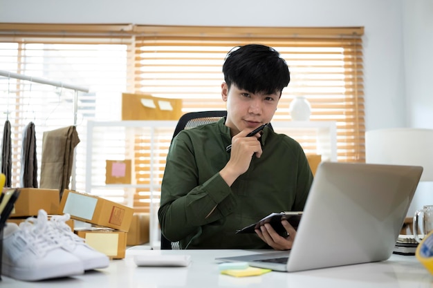 L'homme pigiste vérifie le bon de commande du produit sur un ordinateur portable pendant qu'il travaille au bureau à domicile