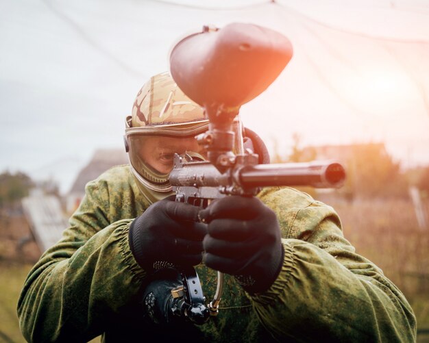 Homme avec pistolet jouant au paintball. En plein air