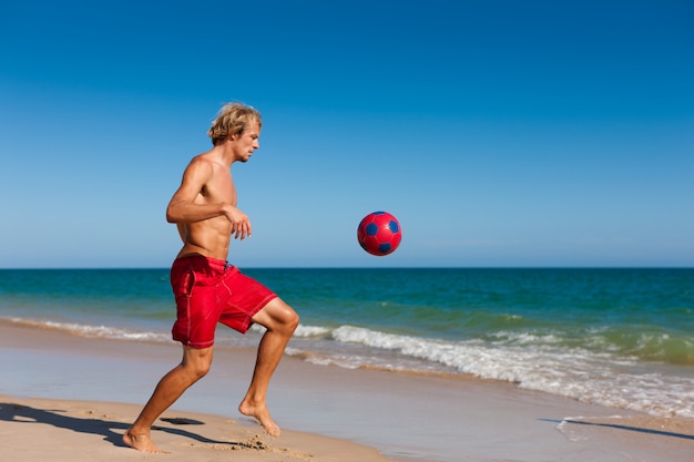 Homme, plage, football jouant