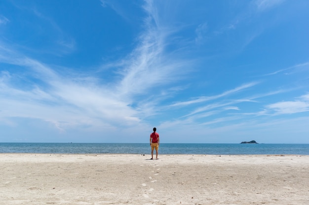 Homme sur la plage avec grand ciel bleu.