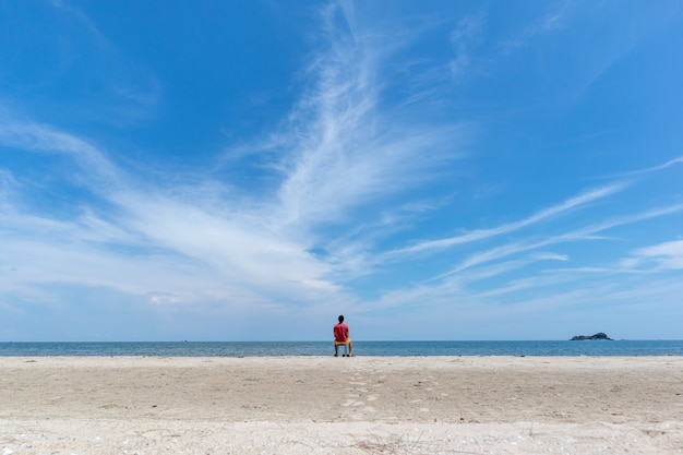 Homme sur la plage avec grand ciel bleu.