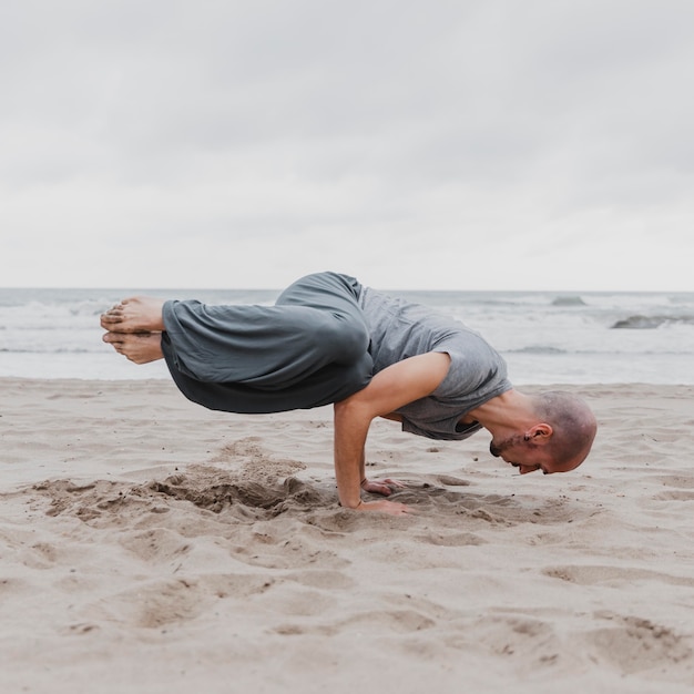 Photo homme sur la plage pratiquant le yoga