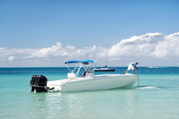 Homme, plaisancier sur bateau à moteur, yacht sur mer, eau de mer, côte ensoleillée d'été en plein air sur fond bleu ciel nuageux à Saint-Jean, Antigua, voyages et vacances, sport et voile