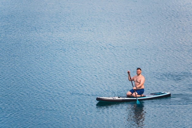 Un homme sur une planche à rames au milieu du lac.