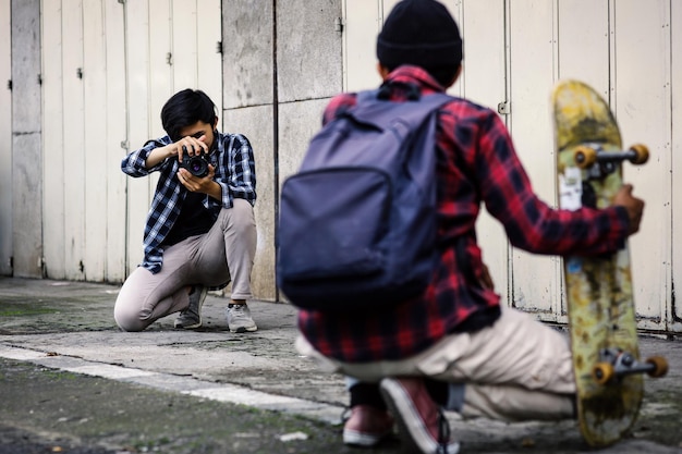 Homme avec planche à roulettes posant pendant que le photographe prend une photo