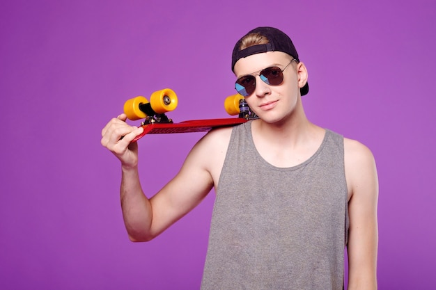 Homme avec planche de skate à la main sur violet