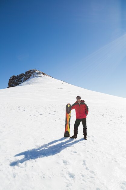 Homme avec planche de ski sur paysage couvert de neige