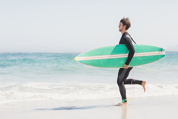 Homme avec planche de surf qui court vers la mer