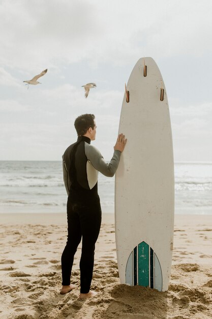 Homme avec une planche de surf regardant la mer