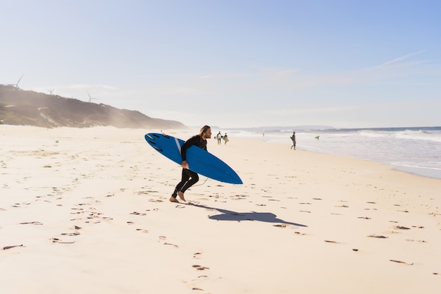 homme avec planche de surf sur la rive de l&#39;océan. Surfer dans un costume de plongée