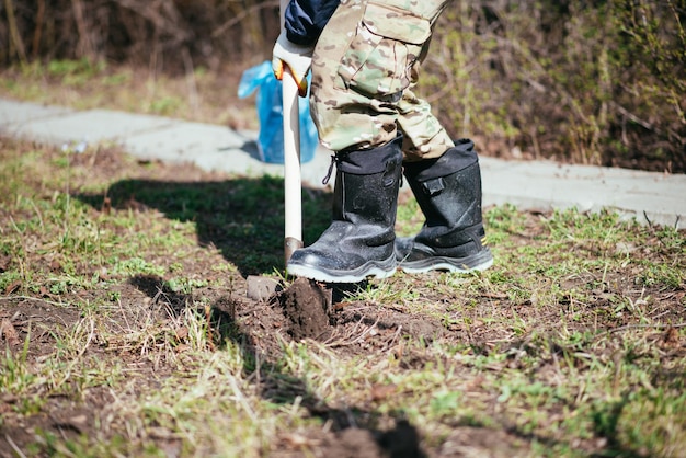 Un homme plante un jeune arbre L'agriculteur creuse le sol avec une pelle pour un petit semis Le concept de protection de l'environnement et de l'écologie