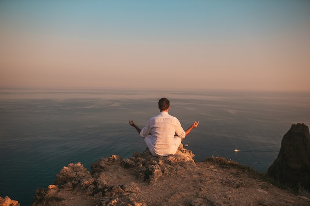 L'homme en plein air blanc sur le bord de la falaise profiter de la vue et médite