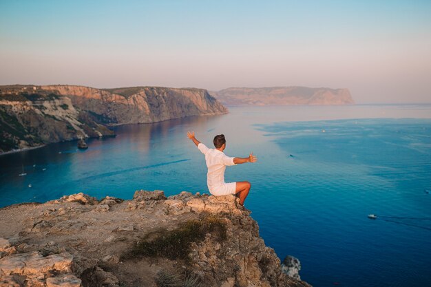 L'homme en plein air blanc sur le bord de la falaise profiter de la vue