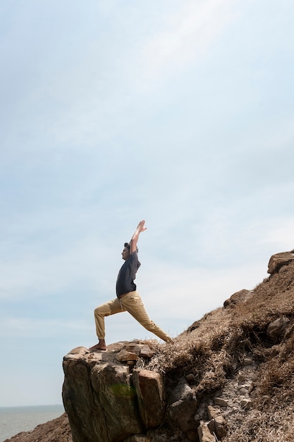 Homme plein coup faisant du yoga sur la plage