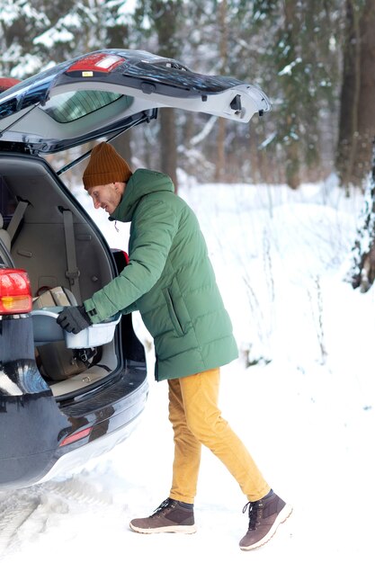 Homme plein coup mettant l'article dans le coffre de la voiture