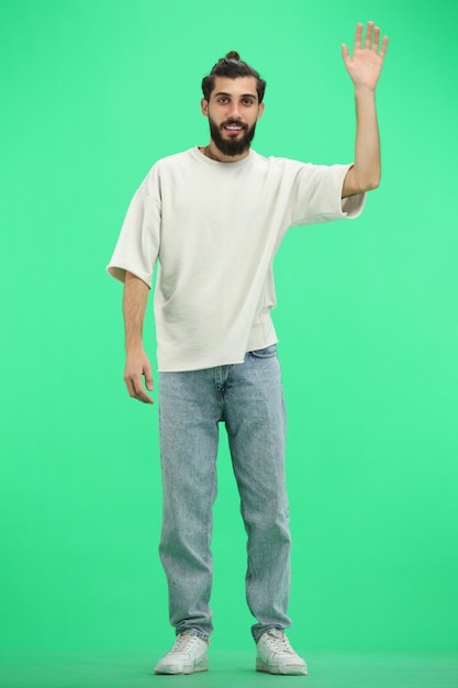 Un homme en pleine longueur sur un fond vert agitant sa main