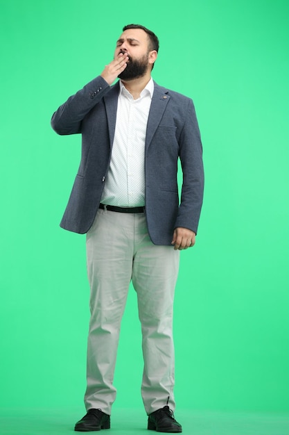 Un homme à pleine longueur sur un fond vert bâille