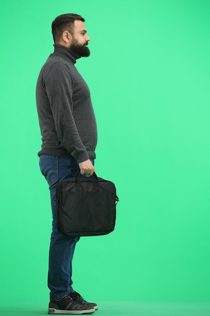 Un homme en pleine longueur sur un fond vert avec une mallette