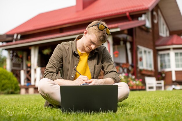 Photo homme en pleine longueur utilisant un téléphone portable dans l'herbe