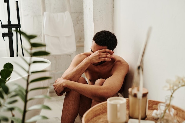 Homme pleurant sur le sol dans la salle de bain