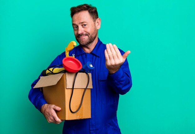 Homme plombier d'âge moyen avec un concept d'entraîneur de sport de boîte à outils avec un ballon de football