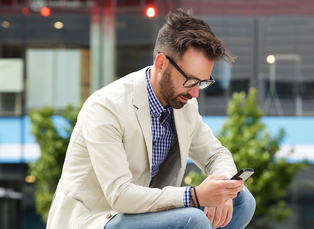 Homme plus âgé assis à l&#39;extérieur et en utilisant un téléphone mobile