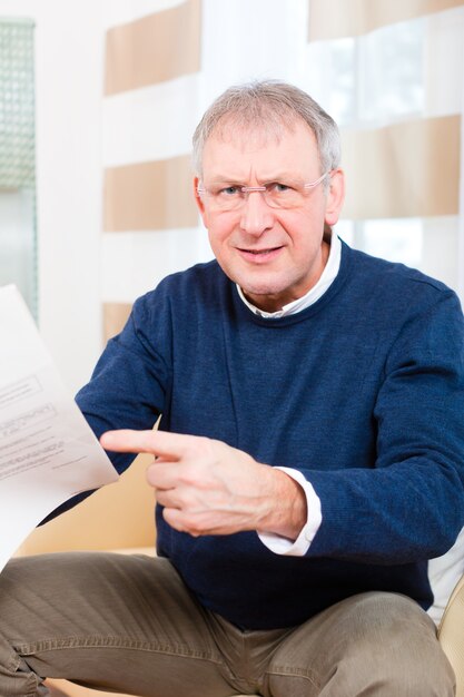 Un homme plus âgé ou un senior a reçu une lettre, peut-être que c'est un rappel ou une facture