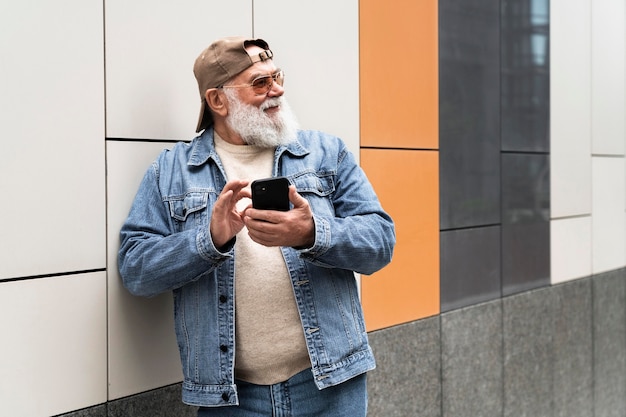 Photo homme plus âgé utilisant un smartphone à l'extérieur de la ville