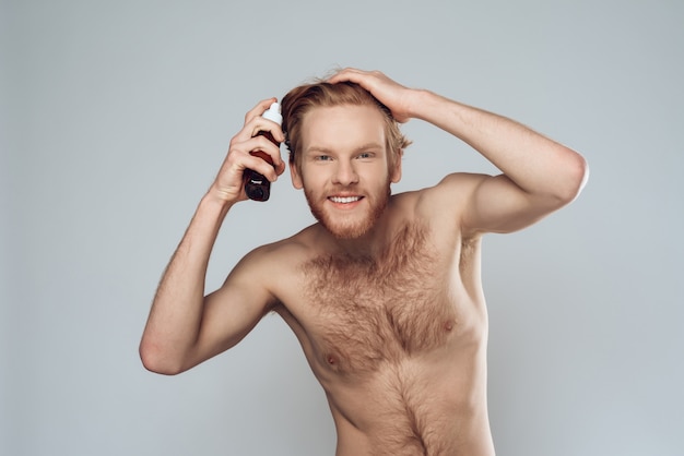 Homme poilu barbu saupoudre de lotion sur les cheveux à la maison.