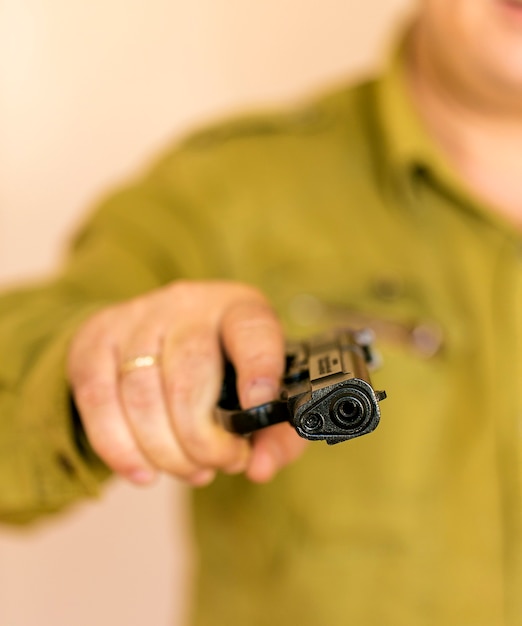 Homme pointant le pistolet sur la cible avec une main, mise au point sélective sur le pistolet avant.