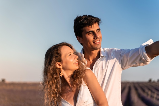 Homme pointant vers l'horizon à côté de son couple dans un champ de lavande