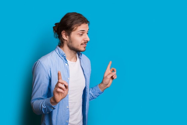 Homme à la pointe de la barbe dans un style hipster sur fond bleu geste de la main bel homme