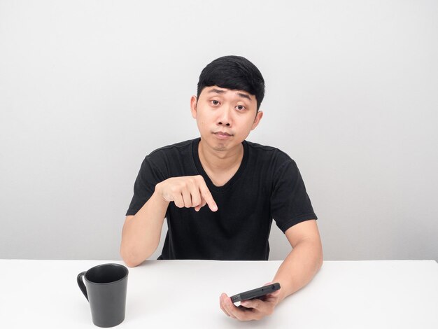 L'homme pointe du doigt le smartphone à la table avec une tasse de café