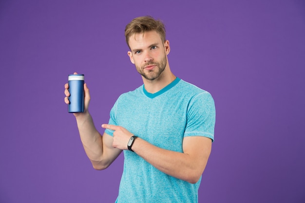 Photo l'homme pointe du doigt le tube de gel sur fond violet. homme barbu tenir une bouteille de shampoing sur fond violet. soins de la peau et des cheveux. santé et soins de santé. cosmétique pour spa et bain ou douche, espace de copie.