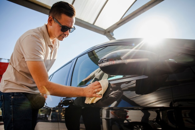 Homme polissant avec soin une voiture noire