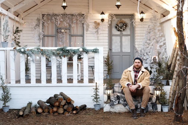 Homme sur le porche de la maison en hiver