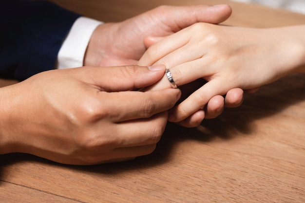 Homme portant la bague de mariage au doigt de la femme.