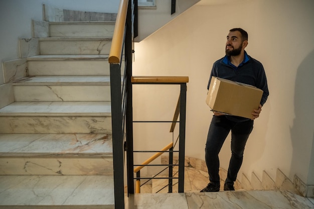 Un homme portant une boîte dans les escaliers