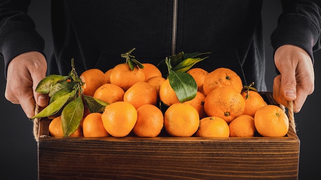 Homme portant une boîte avec des mandarines